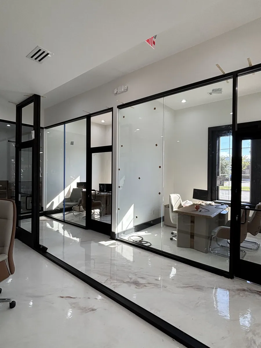 Black-framed glass office walls and doors along a bright hallway