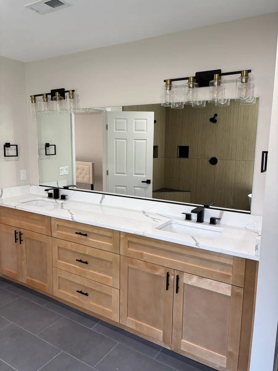 A wide vanity mirror over a double sink with black fixtures